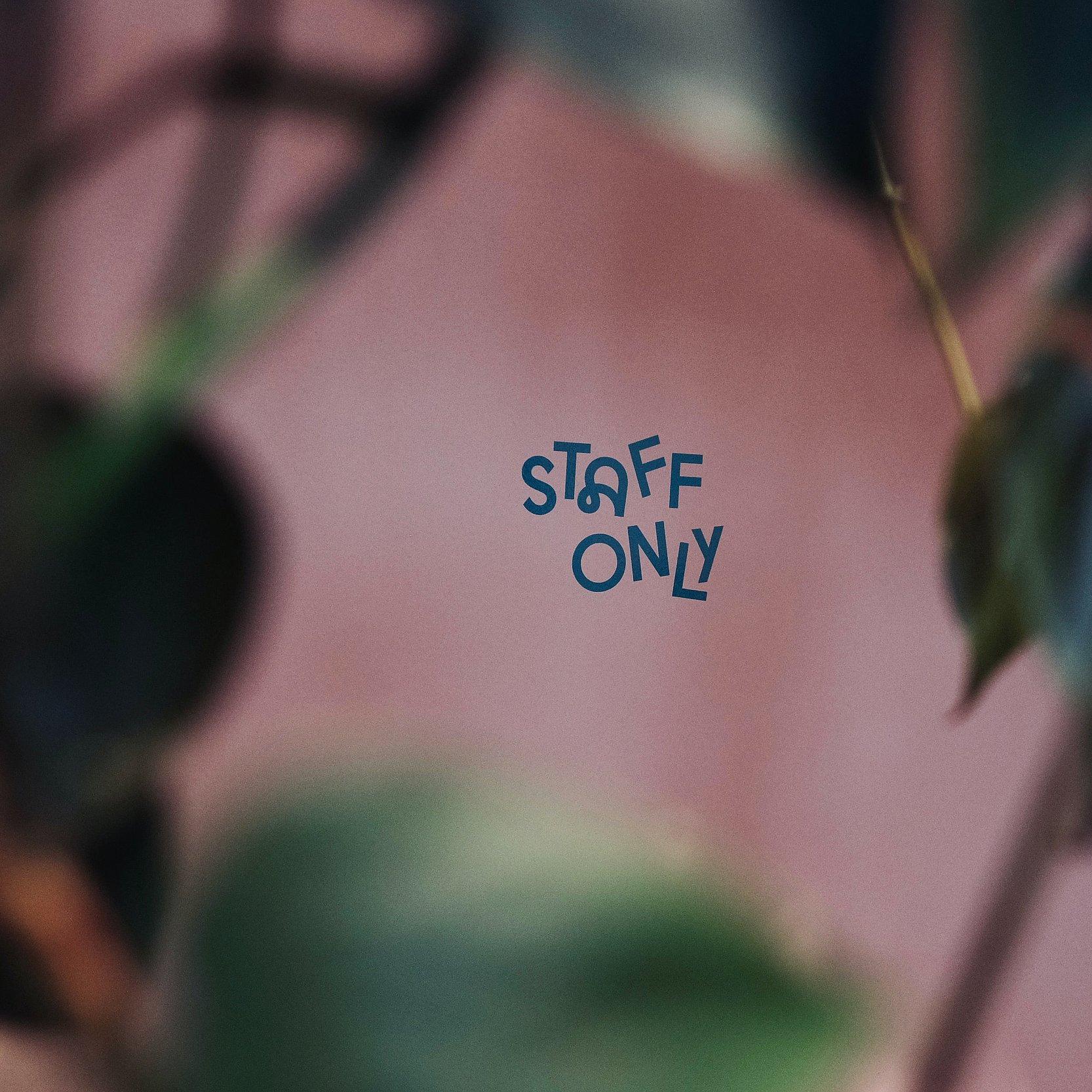 Rosa Wand mit Blättern, darauf steht "Staff only".