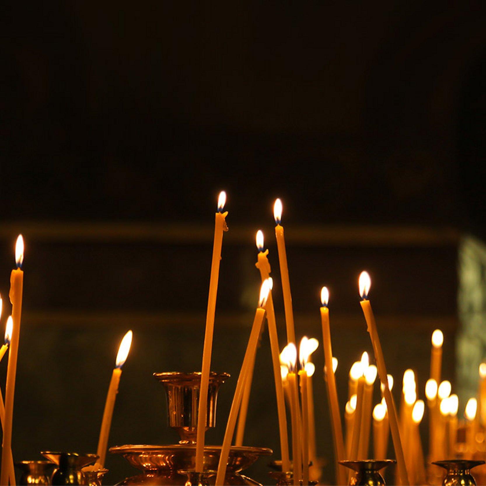 Kerzen Brennende, lange, gelbe Kerzen in einer Kirche
