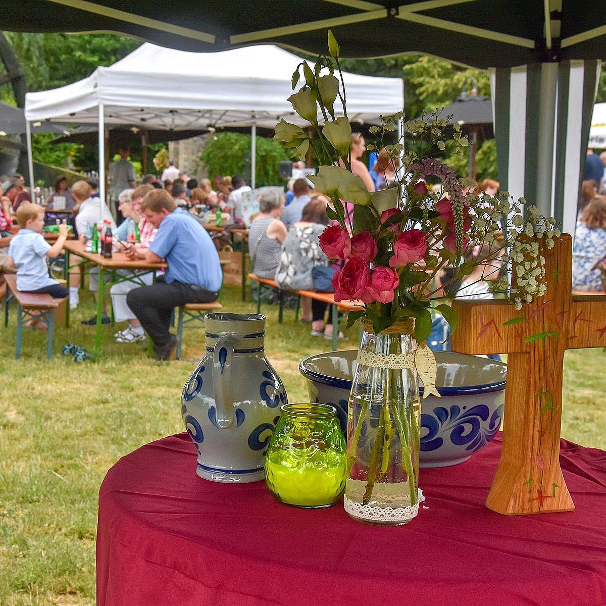 Menschen auf Bierbänken, davor ein Freiluft-Altar