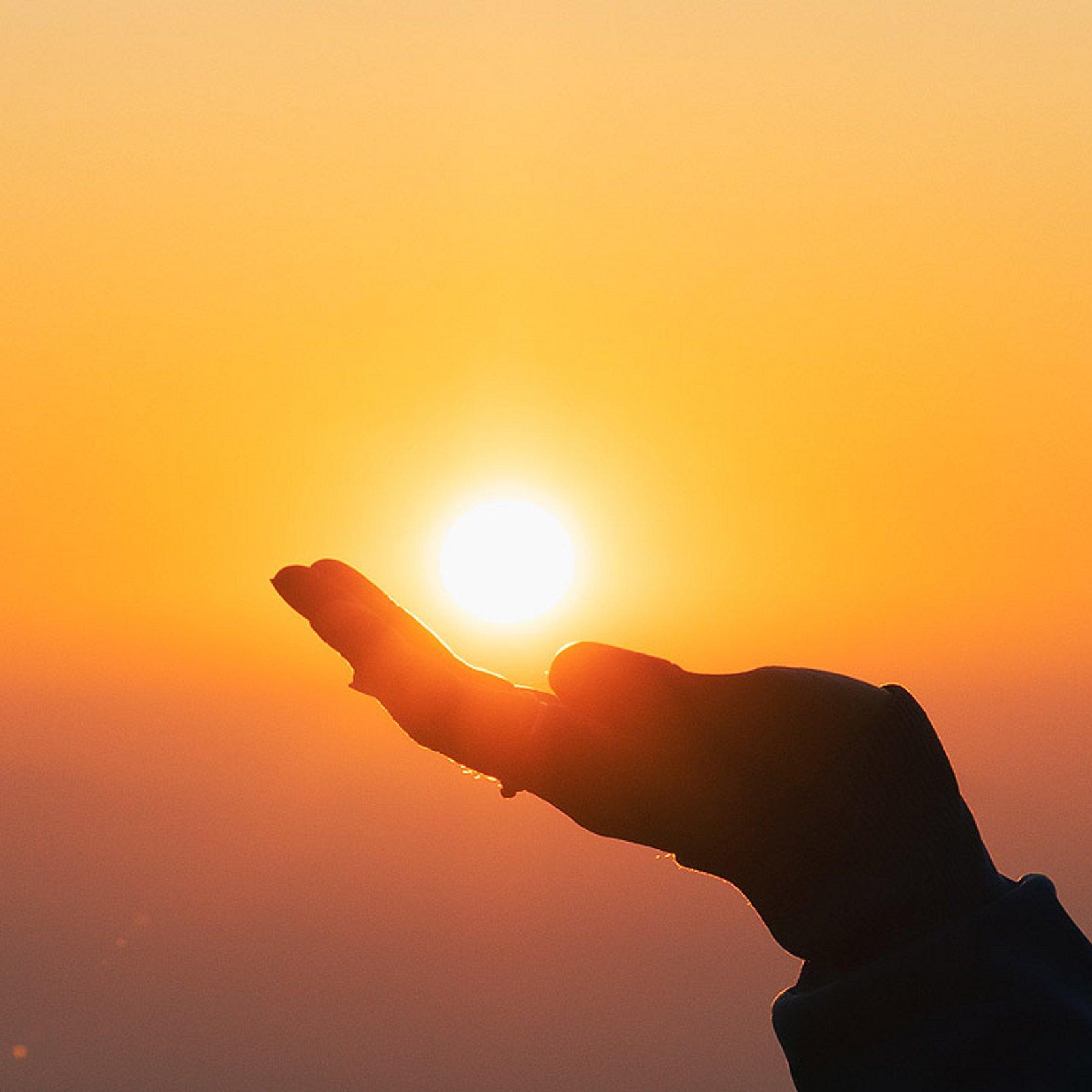Ewigkeit Untergehende Sonne leuchtet über einer Hand