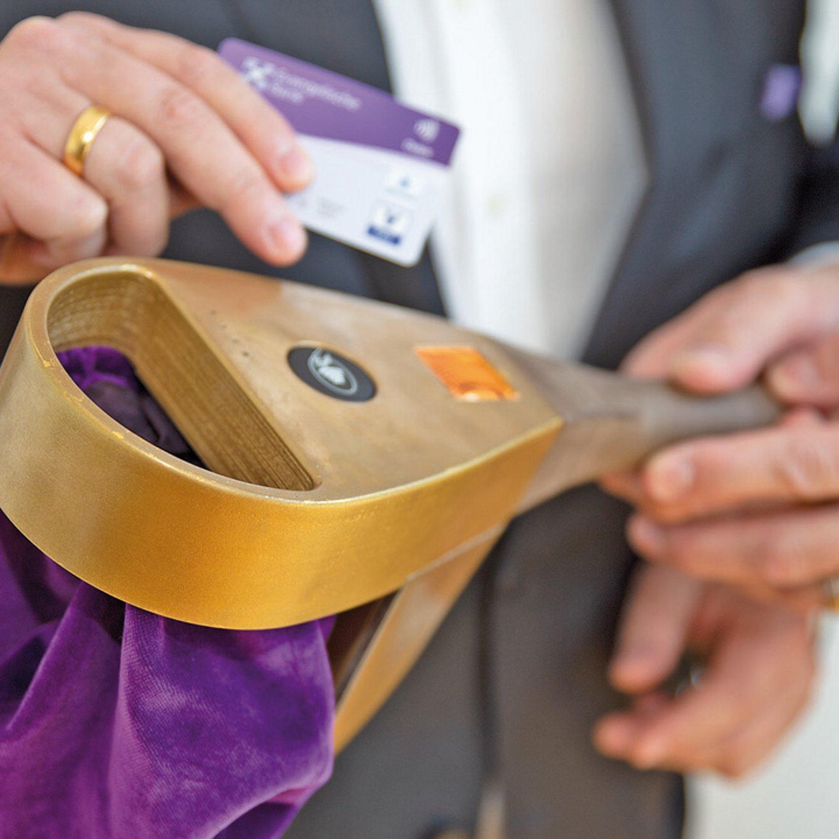 Digitaler Klingelbeutel Ein Klingelbeutel, jemand hält eine EC-Karte daran.