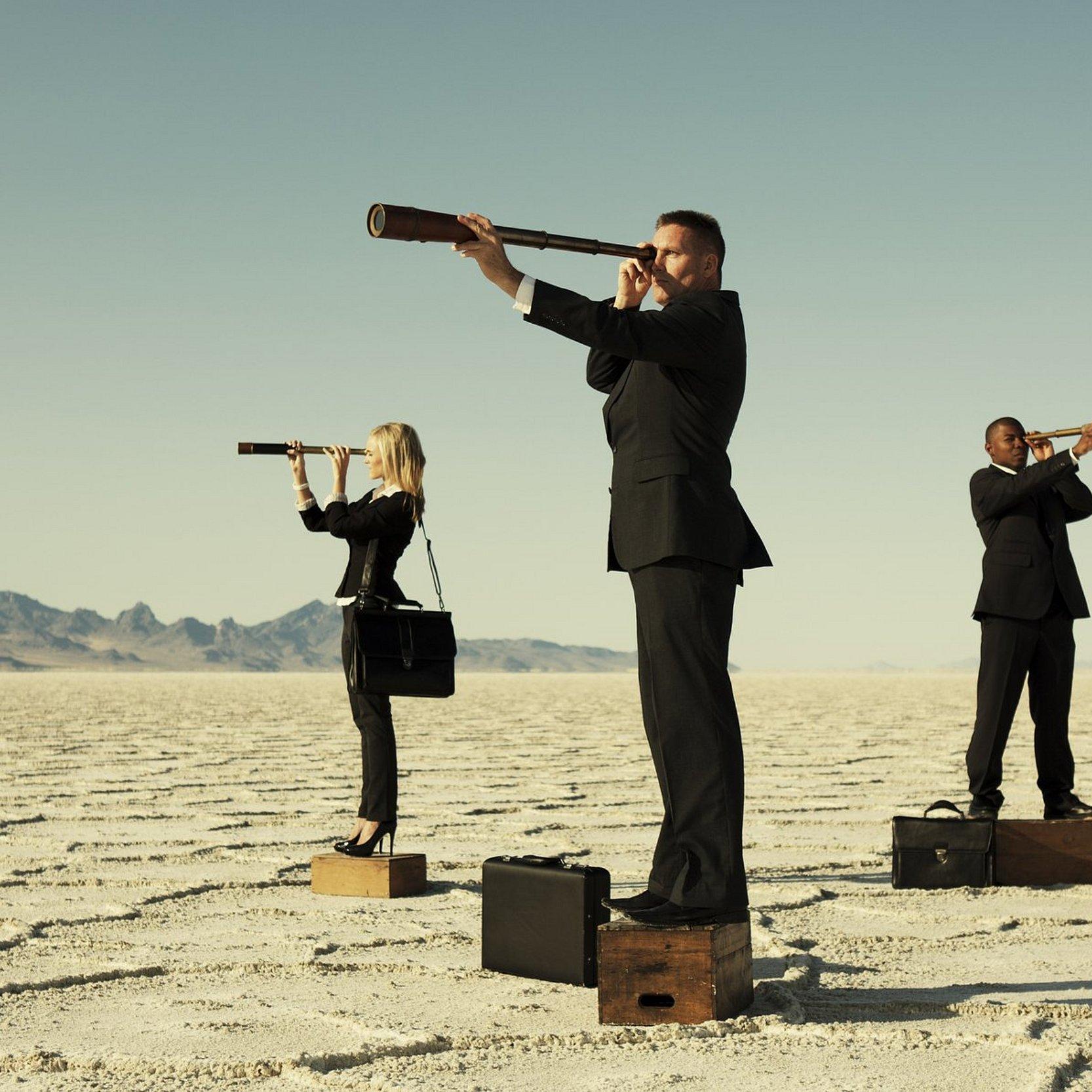 Business-Team Drei Geschätsleute mit Fernrohren in einer Wüstenlandschaft