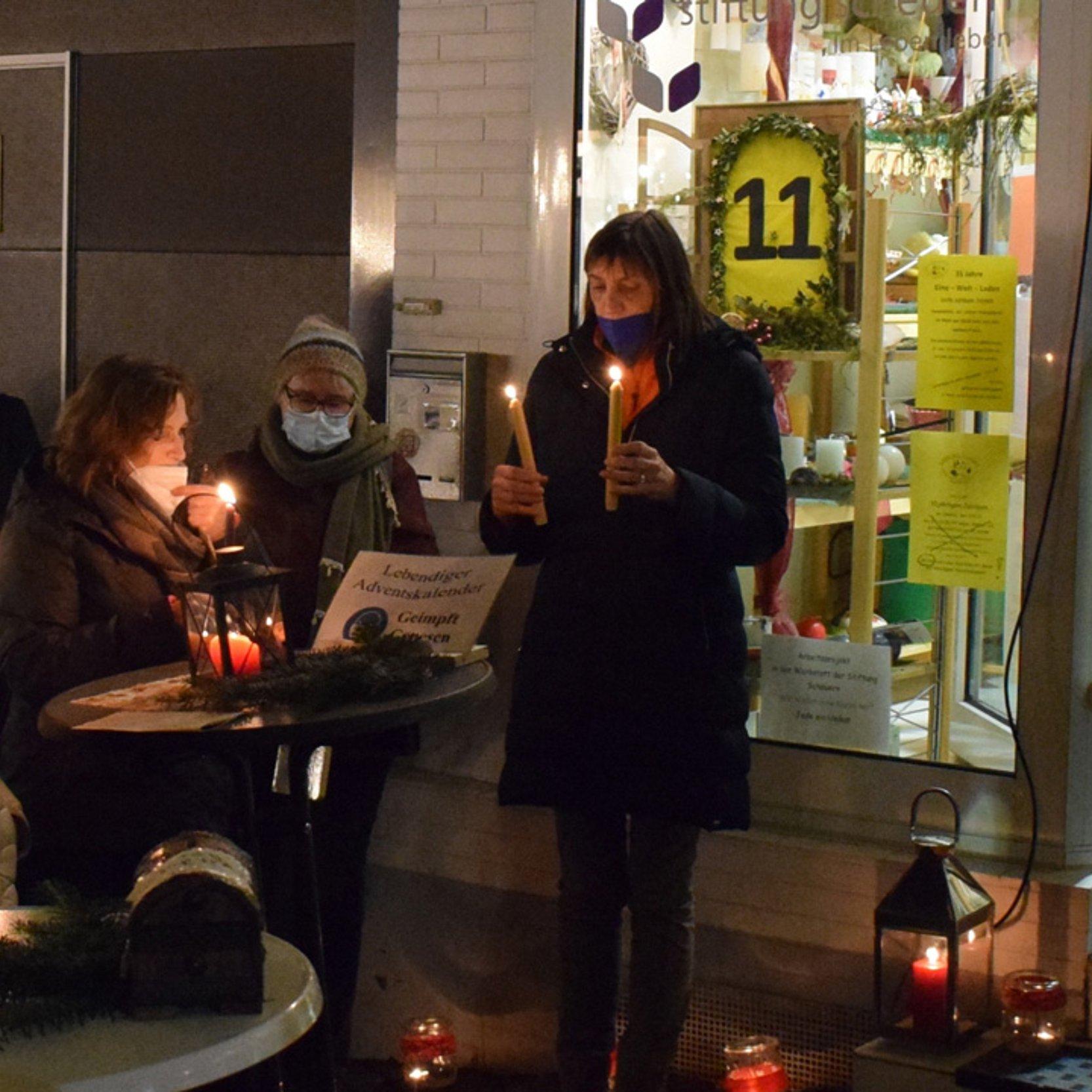 Ein paar Menschen vor einem kleinen Laden musizieren und es brennen Kerzen