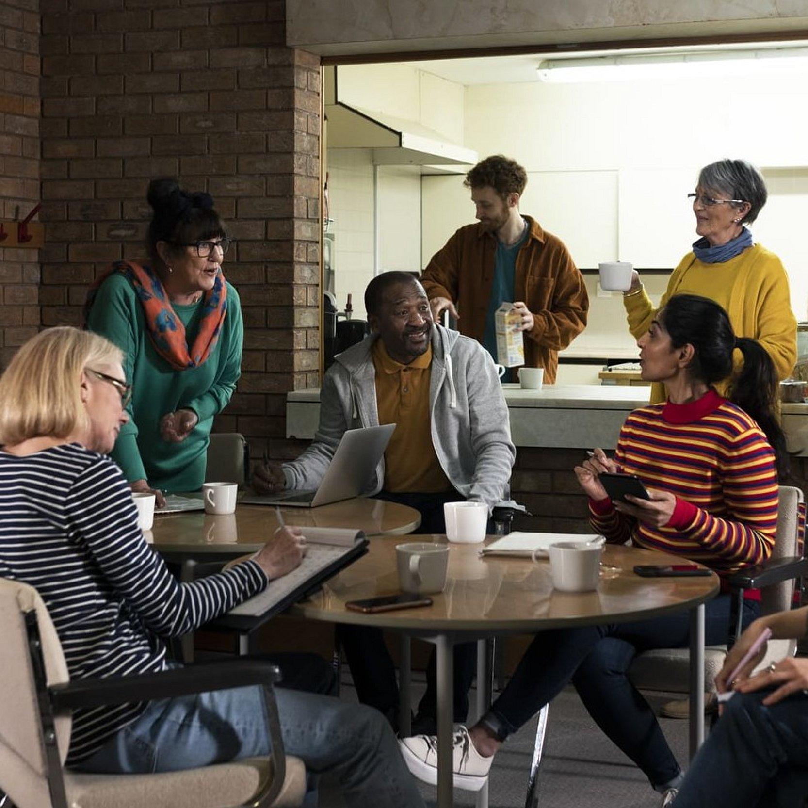 Gemeinde entscheidet über Kirchenasyl Eine Gruppe von Menschen sitzt in einem Gemeinderaum beisammen, darunter auch Menschen mit Migrationshintergrund. Sie bilden einen gemütlichen Sitzkreis.
