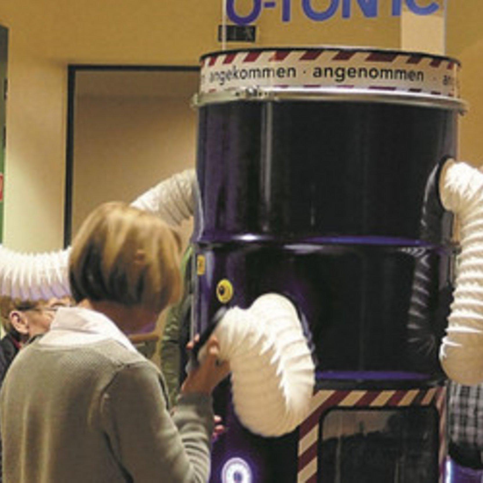 Installation O-Tonne Menschen halten sich Hörschläuche an die Ohren