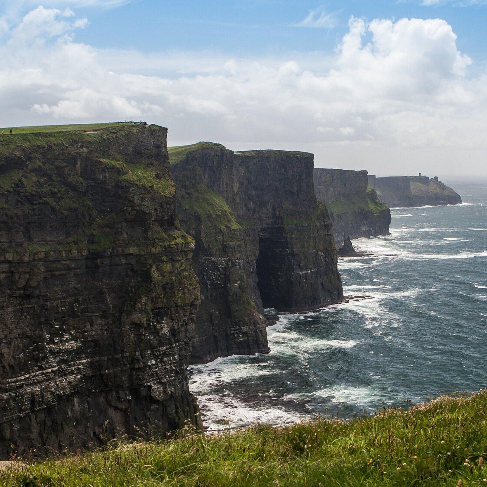 Im Sonnenlicht mit Meeresgicht ragen die steilen Cliffs of Moher aus dem Meereswasser in Irland.