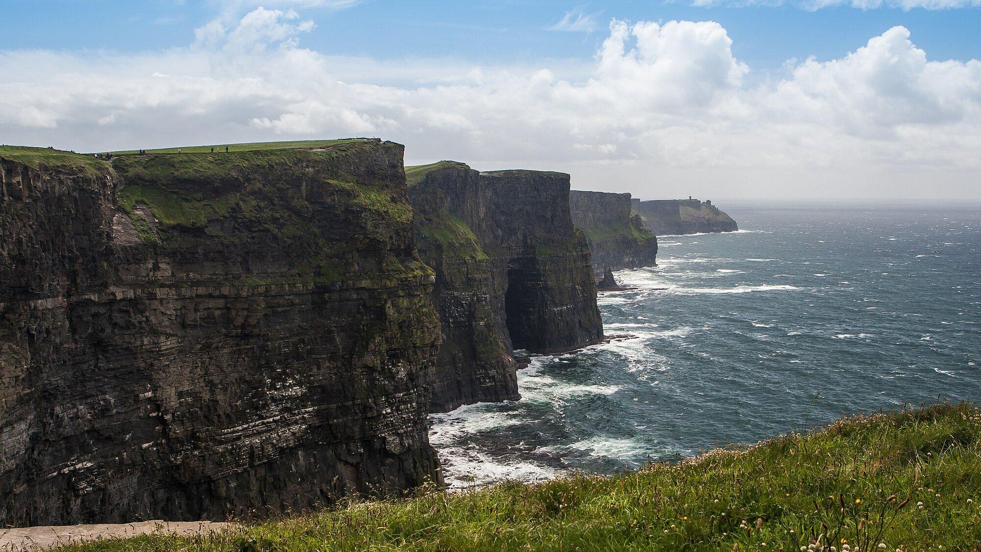 Im Sonnenlicht mit Meeresgicht ragen die steilen Cliffs of Moher aus dem Meereswasser in Irland.