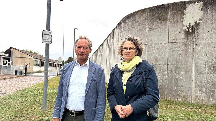Gewahrsamseinrichtung für Ausreisepflichtige Zwei Personen vor einer grauen Mauer