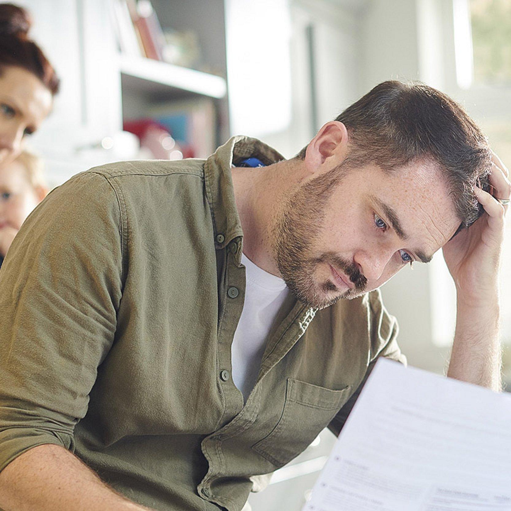 Wohnungskündigung Eine Familie bekommt einen Brief, der Mann starrt entsetzt auf das Blatt