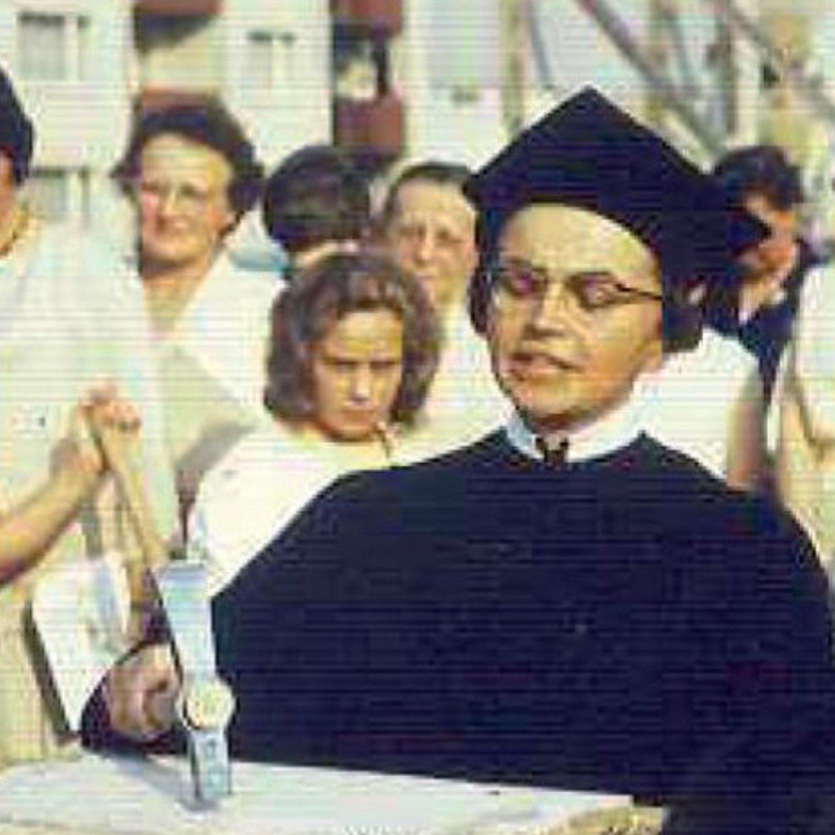 Waltraud Hübner 1963 Pfarrerin im alten schwarzen Talar mit schwarzer Haube haut mit einem Hammer auf einen Stein im Hintergrund stehen Menschen im Halbkreis und schauen ihr zu.