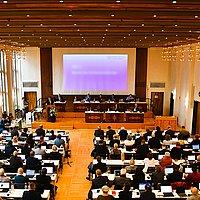 Plenum der EKHN-Synode Großer Saal mit Leinwand am Ende, davor viele Bankreihen mit Menschen