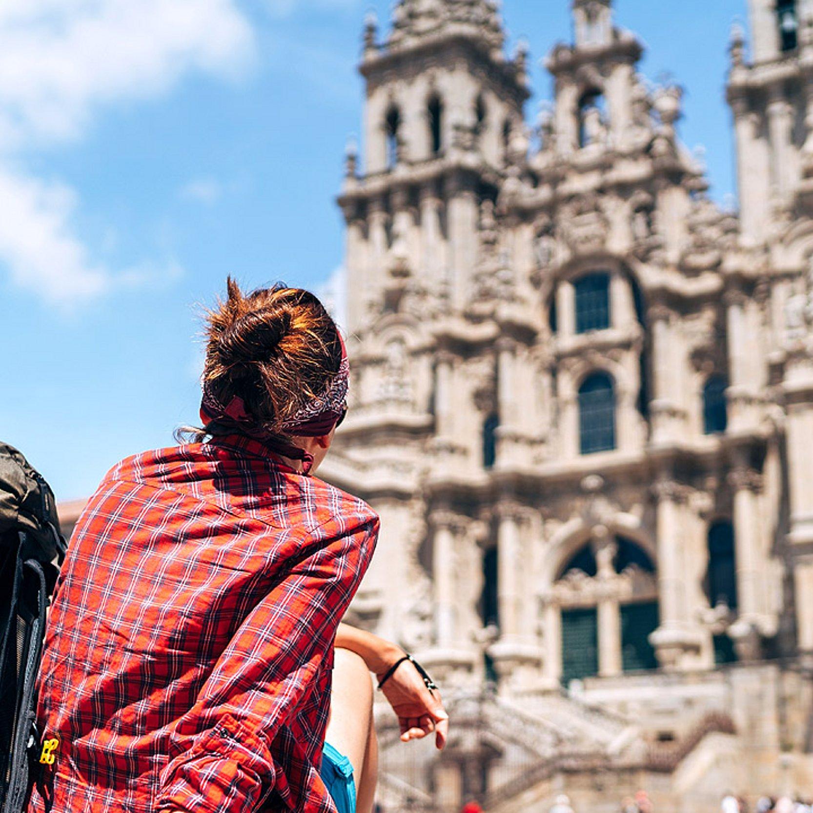Santiago de Compostela Eine Frau mit Rucksack sitzt vor der Kathedrale in Santiago
