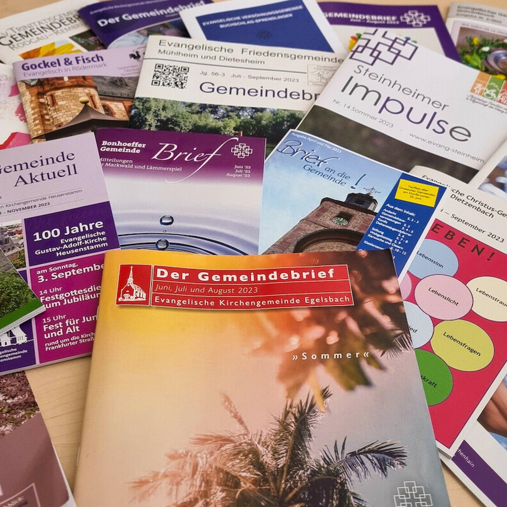 Gemeindebriefe Man sieht viele unterschiedliche Gemeindebriefe in verschiedenen Formaten, Farben und Gestaltungen