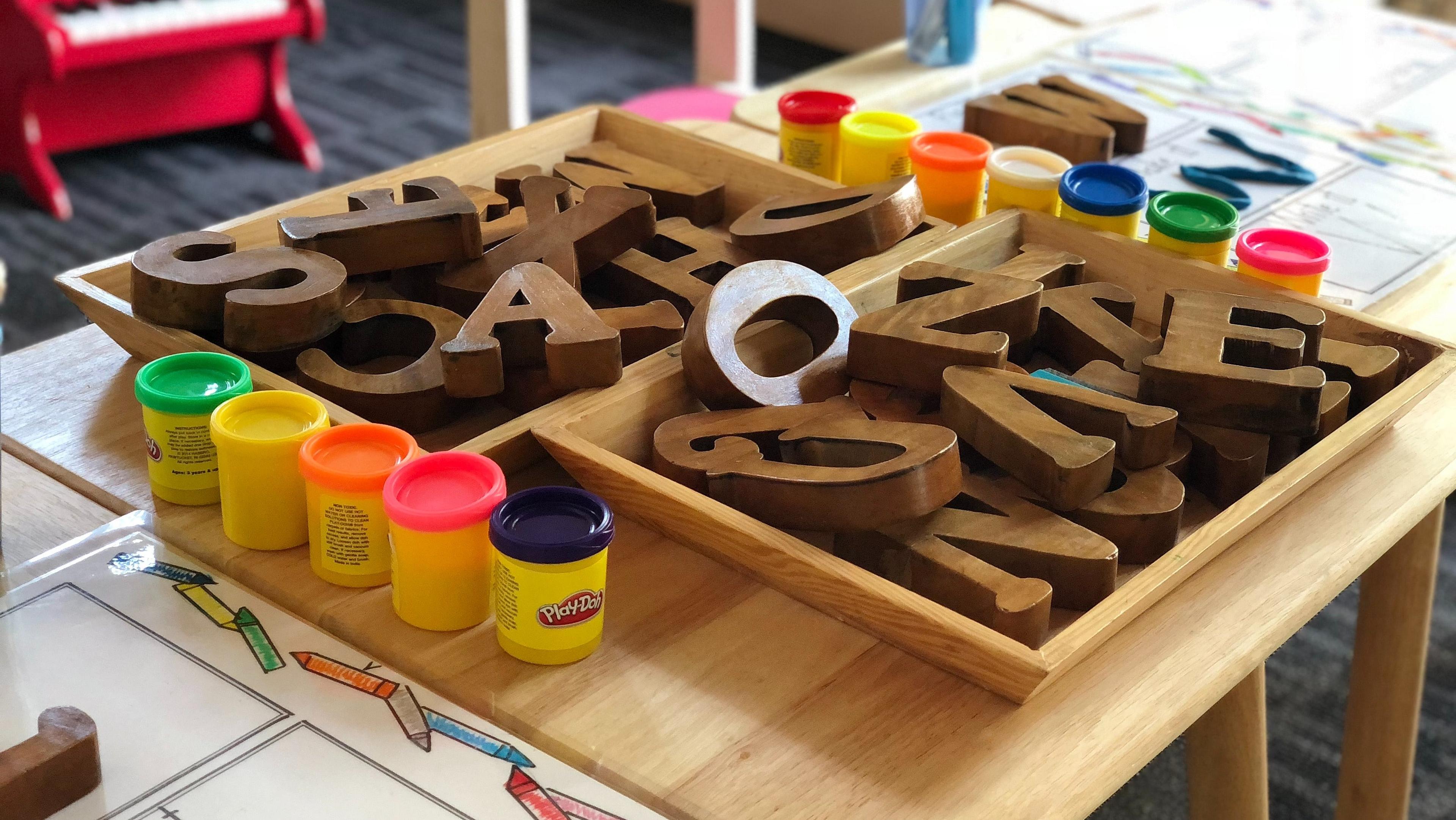 Holzbuchstaben und Knete auf einem Tisch in der Kita.