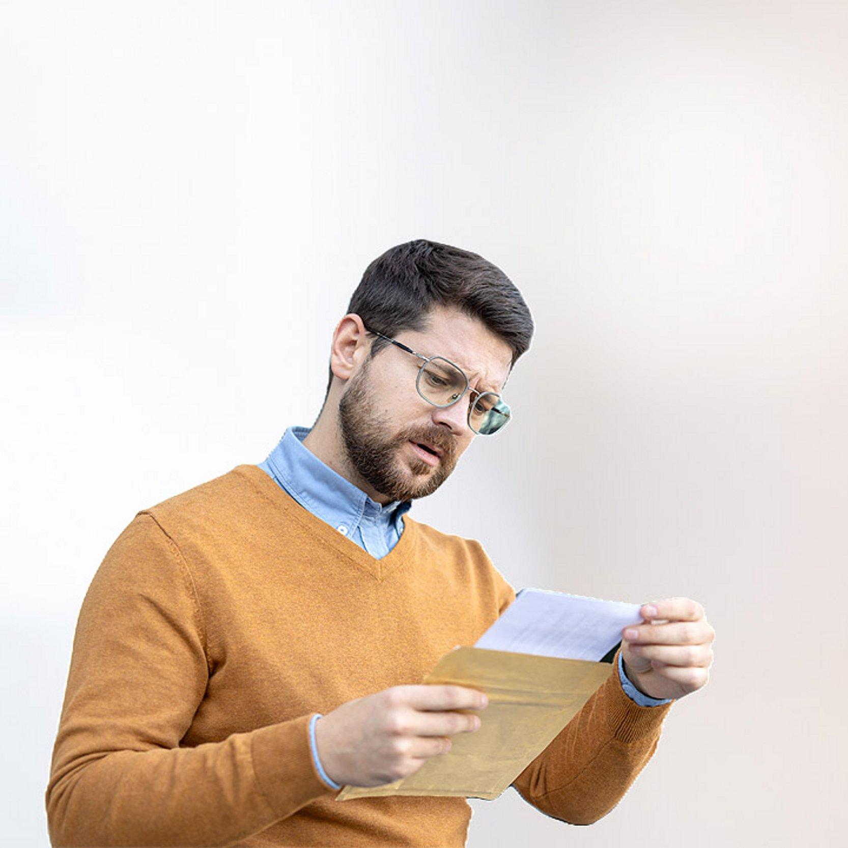 Abfindung Ein Mann blickt sorgenvoll auf einen offiziellen Brief