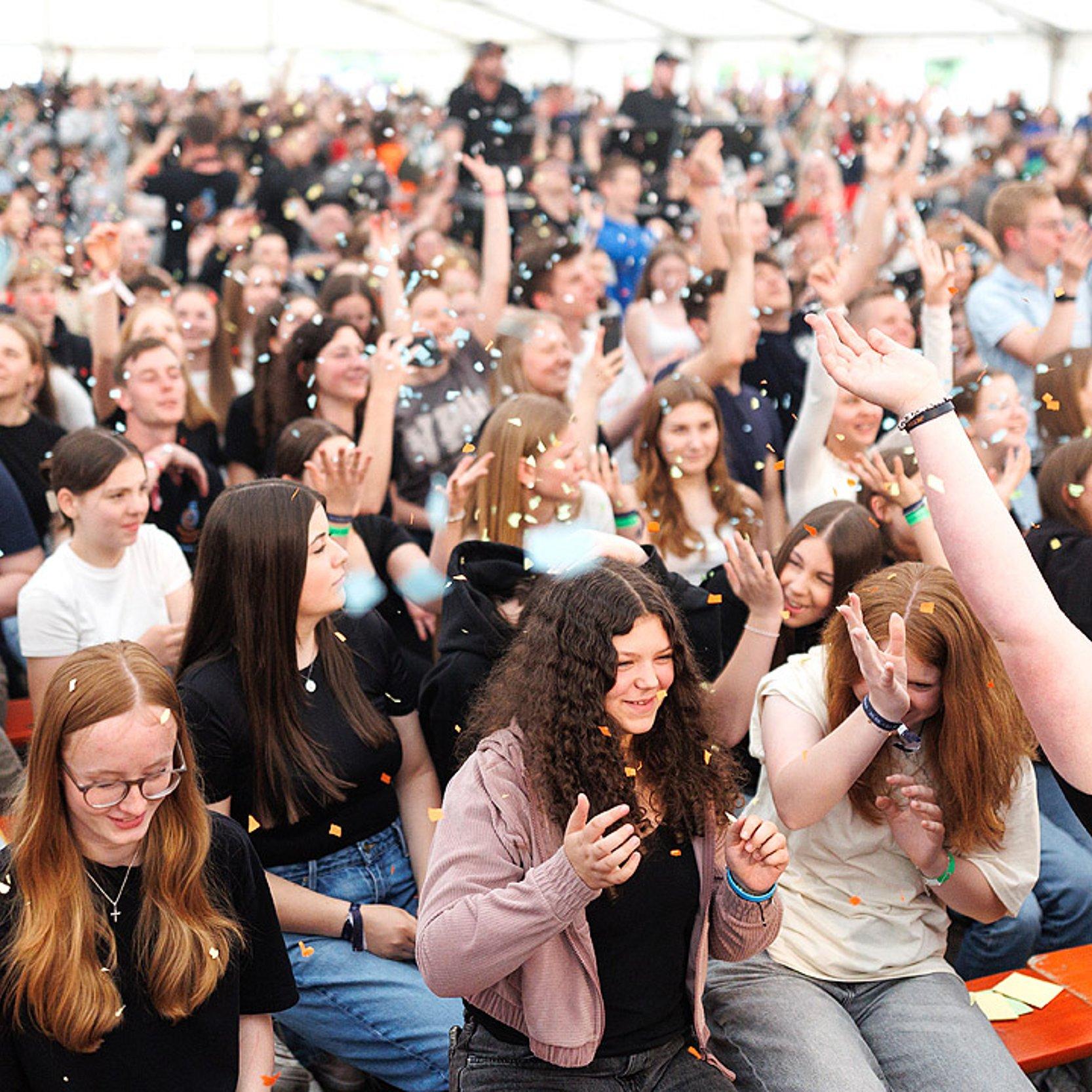 Jugendkirchentag Jubelnde Jugendliche, darüber riesendes Konfetti