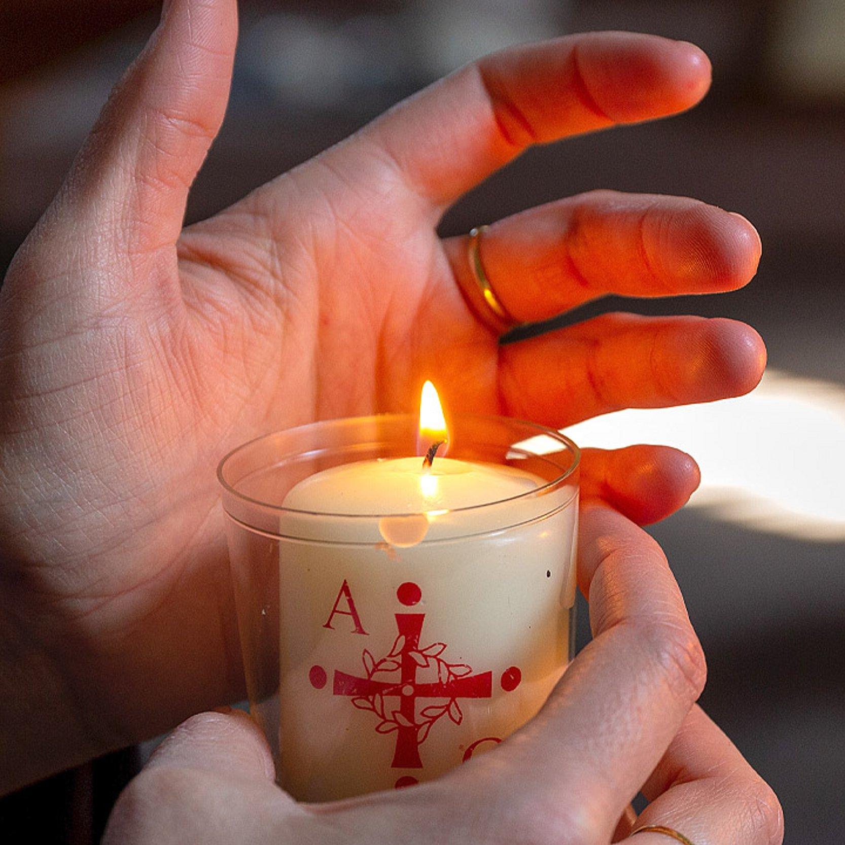 Osterkerze Hand hinter einer kleinen Osterkerze