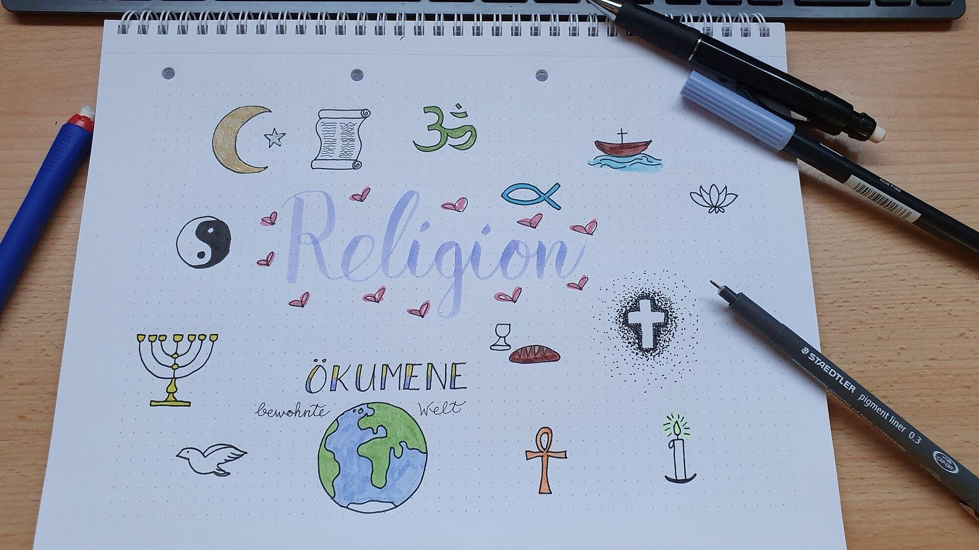 Auf einen Zeichenblock gemalte Symbole der Weltreligionen