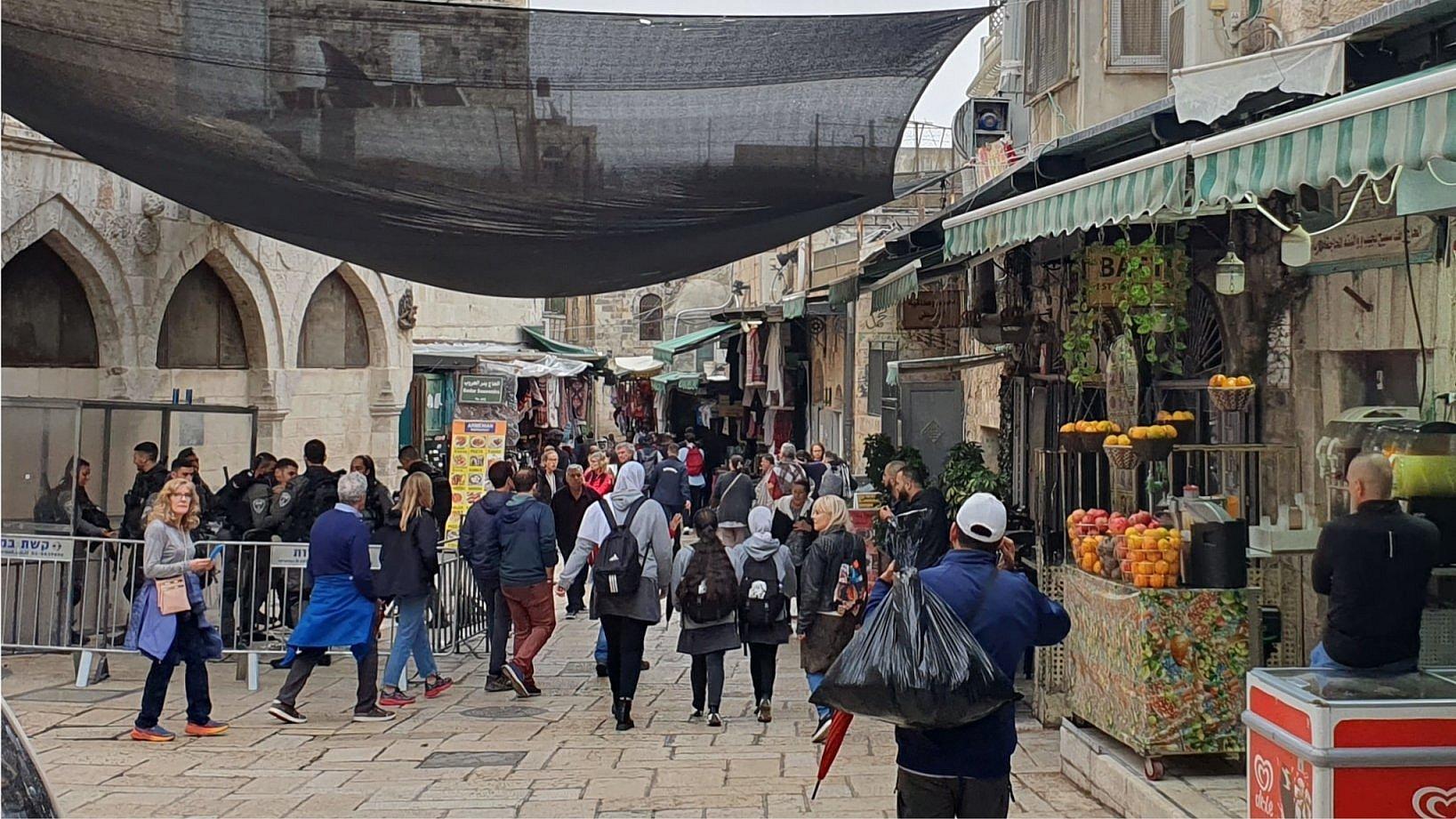 Ein belebte Straße in der Jerusalemer Altstadt. Israelische Sicherheitskräfte haben dort einen Posten errichtet. Touristen und Einheimische laufen vorbei.