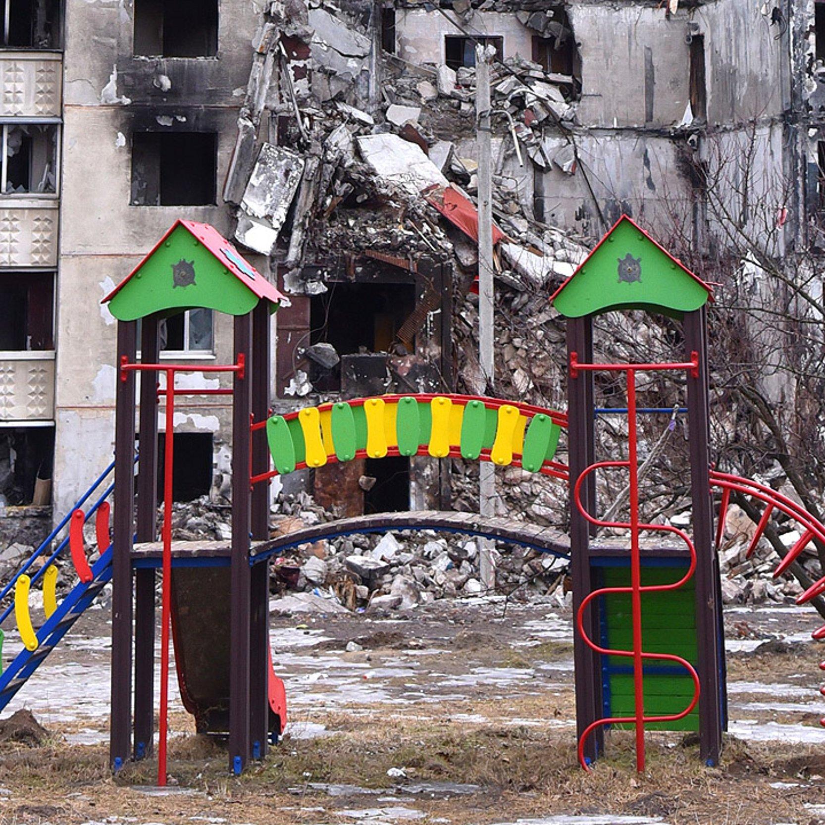 Krieg in der Ukraine Zerstörtes Haus im ukrainischen Charkiw hinter einem Kinderspielplatz
