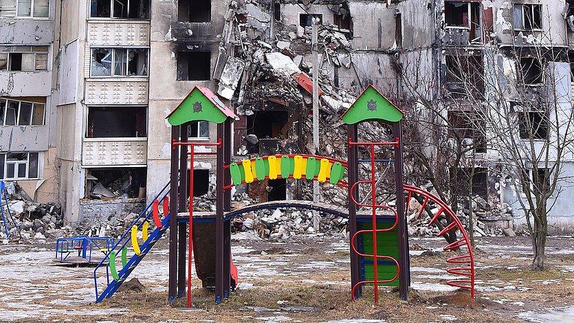 Zerstörtes Haus im ukrainischen Charkiw hinter einem Kinderspielplatz