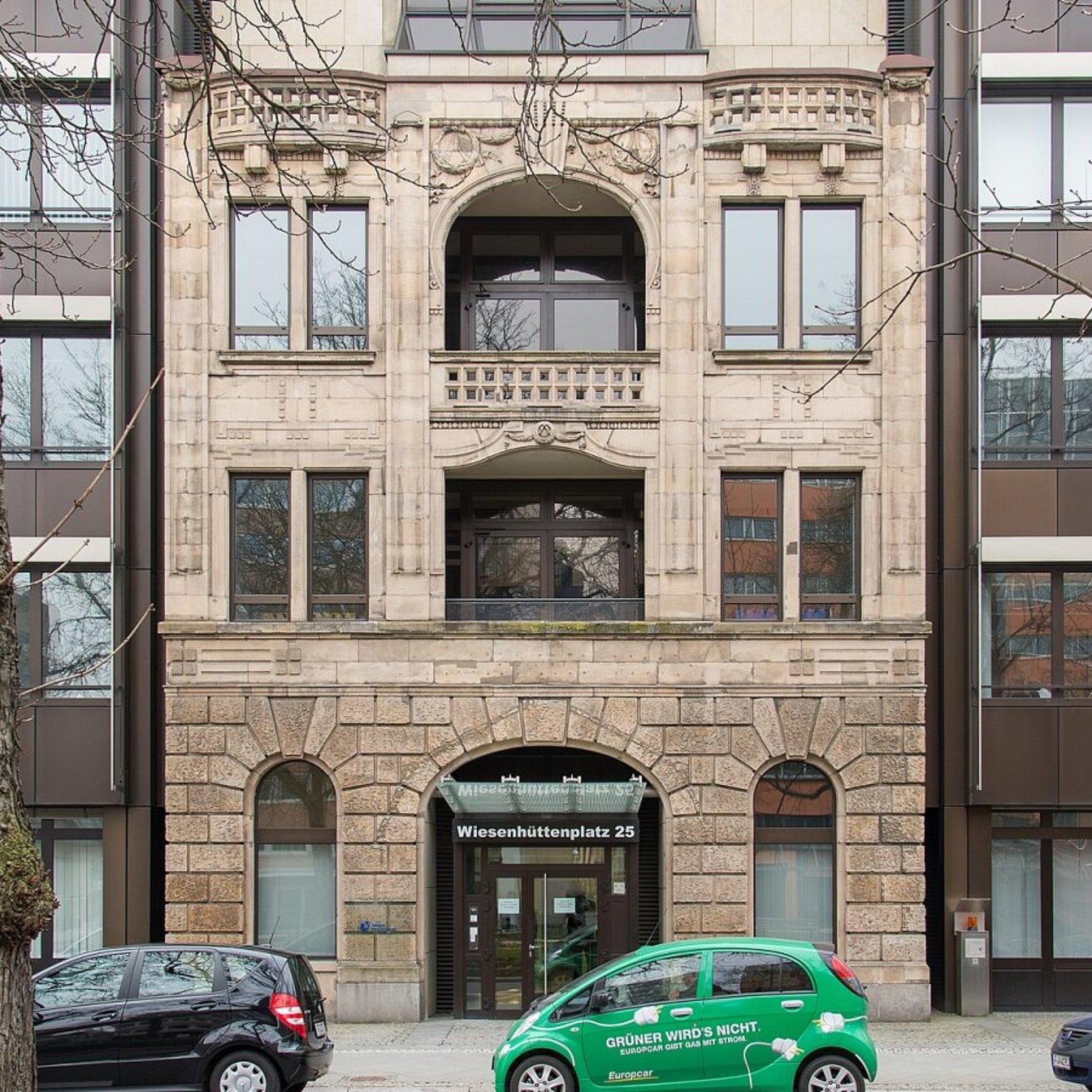 Ansicht der historischen Gebäudefassade inmitten von Neubauten.