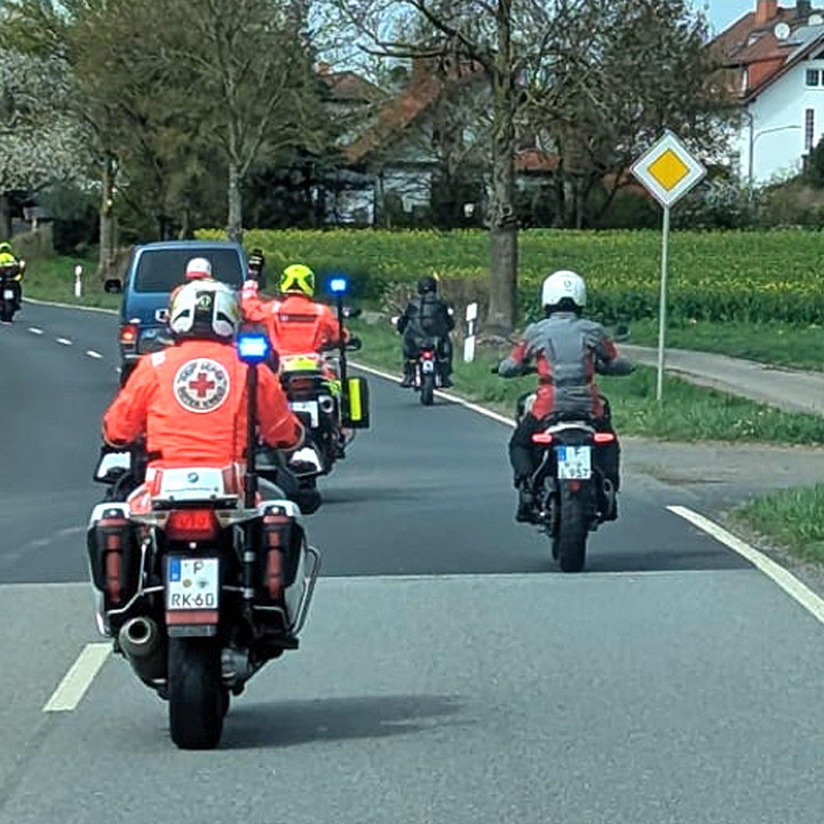 Christliche Biker unterwegs Gruppe von Motoarradfahrern fährt in einen Ort, Menschen winken am Straßenrand
