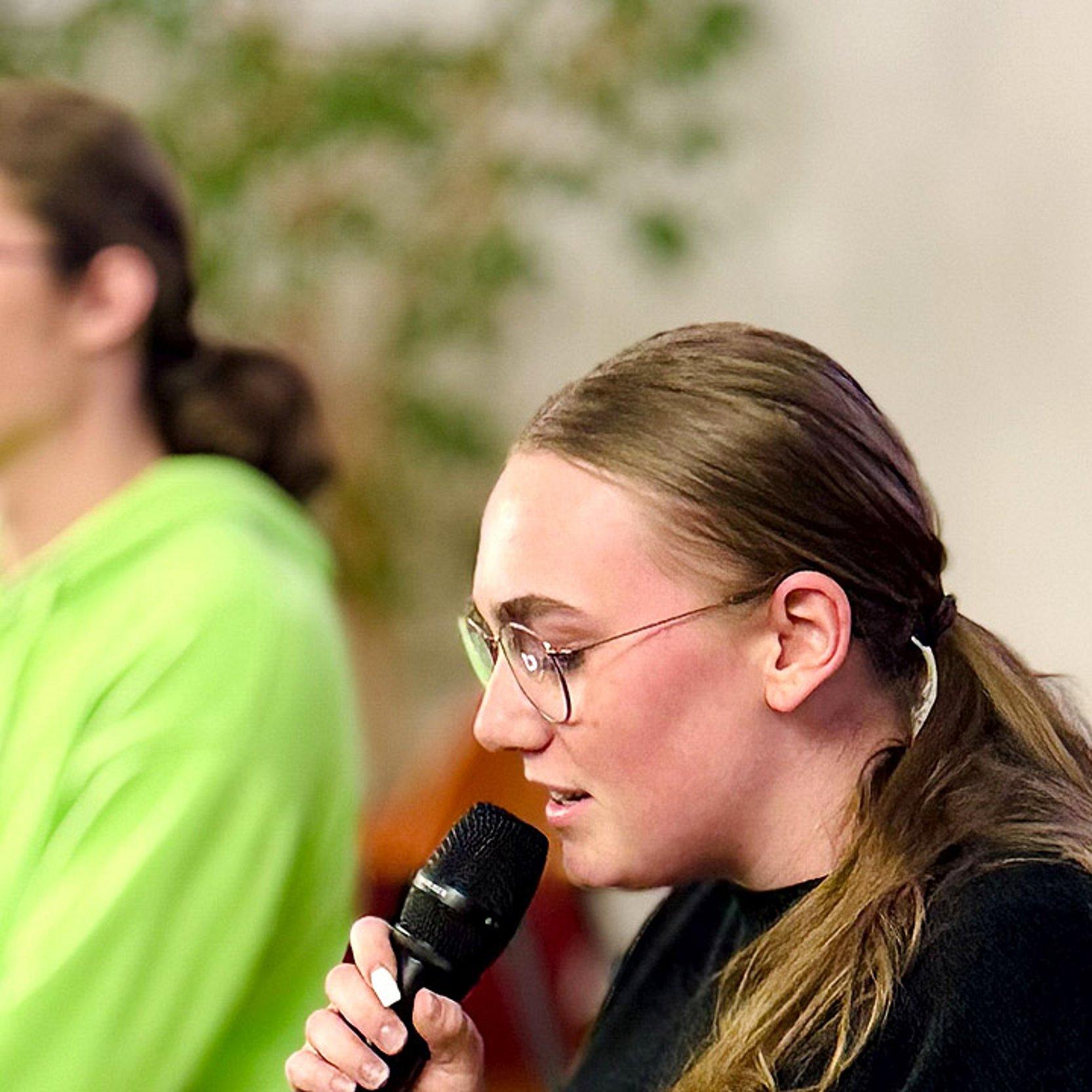 Jugendkirchentagsmotto Junge Rednerin mit Mikrofon