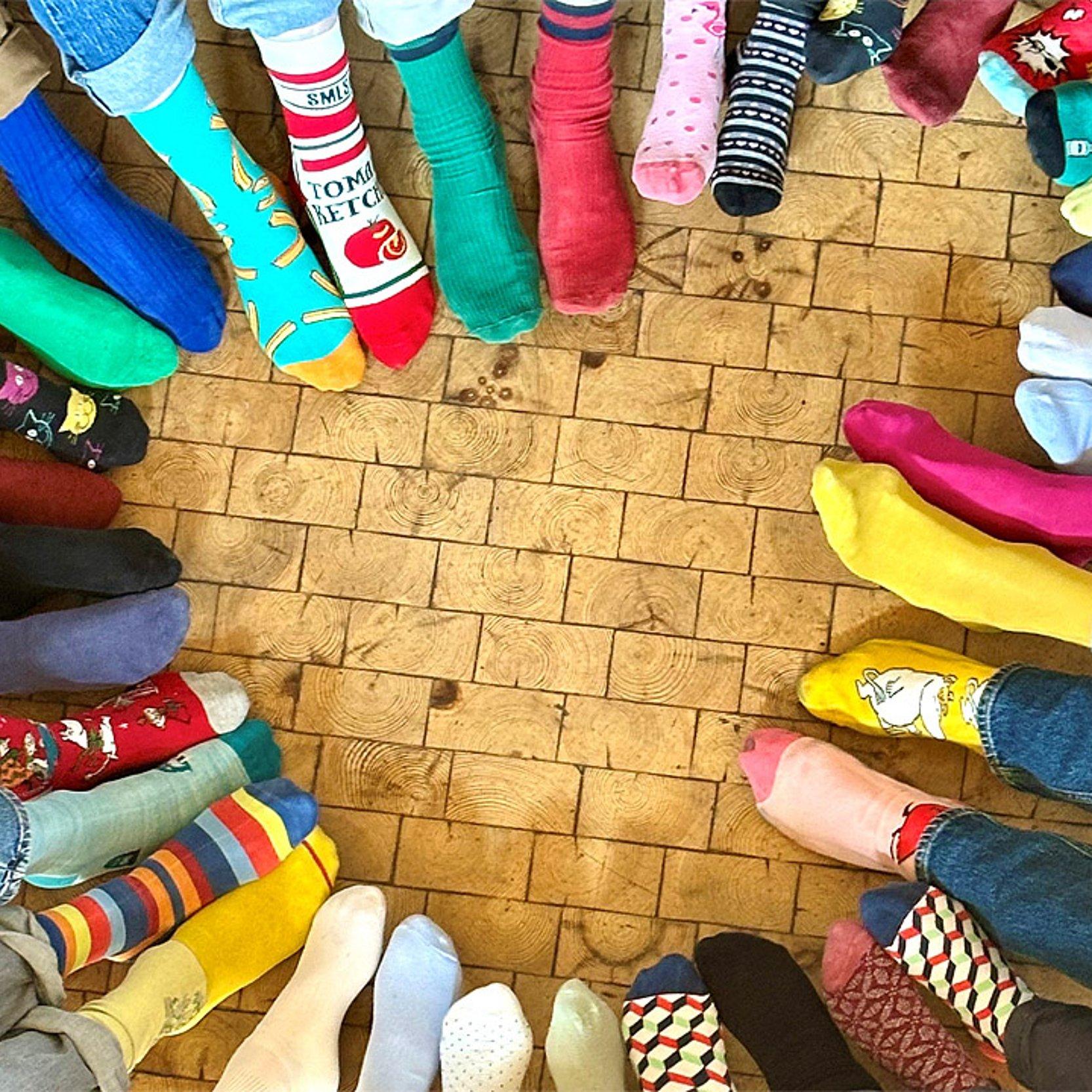 Dekane mit coolen Socken Viele Füße mit bunten Socken formen ein Herz