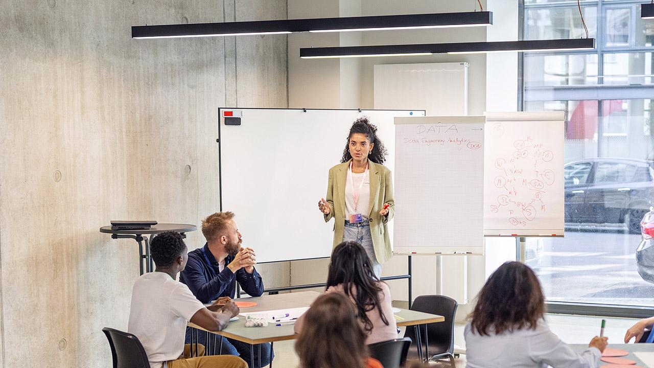 Bildung Menschen im halben Stuhlkreis vor einer Dozentin