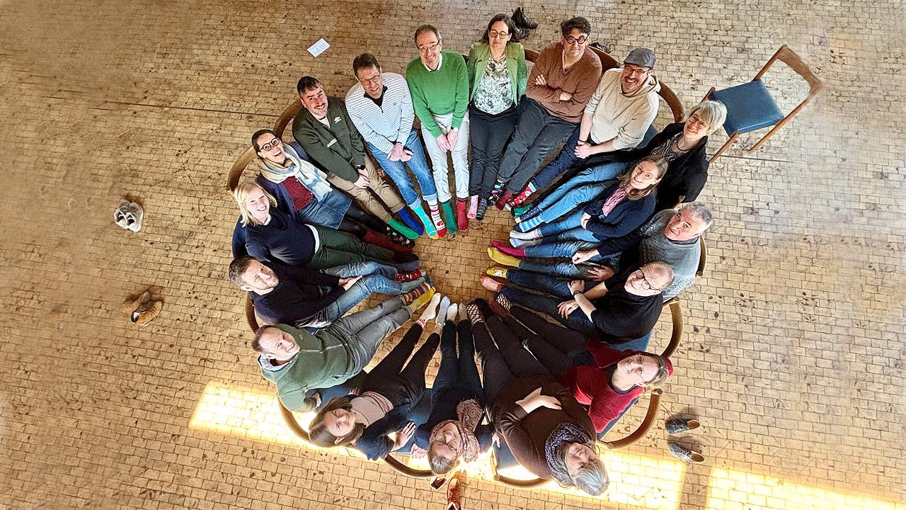 Coole Socke Menschen sitzen im Kreis und strecken ihre Füße mit bunten Socken in die Mitte, von oben fotografiert