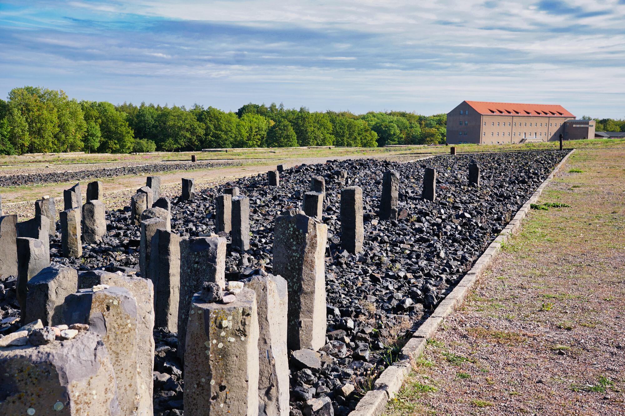 Gedenken an die Sinti und Roma; KZ Gedenkstätte Buchenwald Gedenken an die Sinti und Roma; KZ Gedenkstätte Buchenwald. Gedenksteine im Bildvordergrund. Im Hintergrund ein Gebäude, am rechten Bildrand Bäume und oben blauer Himmel mit Wolken.