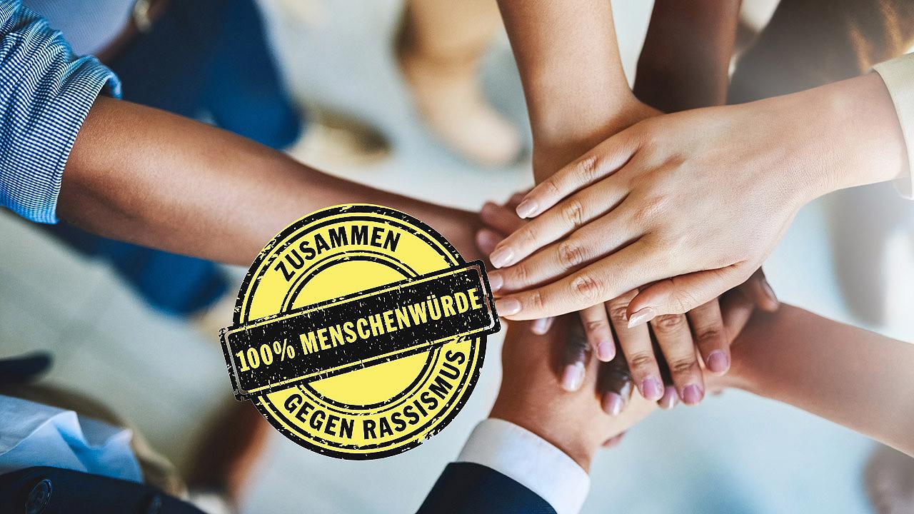 Menschen unterschiedlicher Hautfarbe legen ihren Hände übereinander