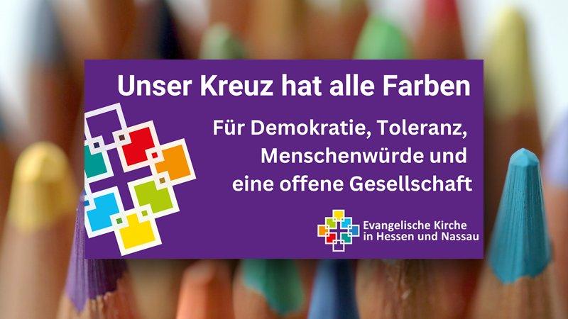Unser Kreuz hat alle Farben Buntes Facettenkreuz und Slogan, im Hintergrund Buntstifte