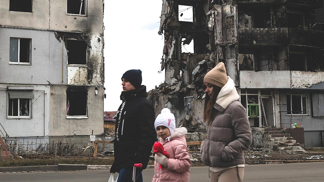 Familie läuft an Mietshaus-Ruinen vorbei