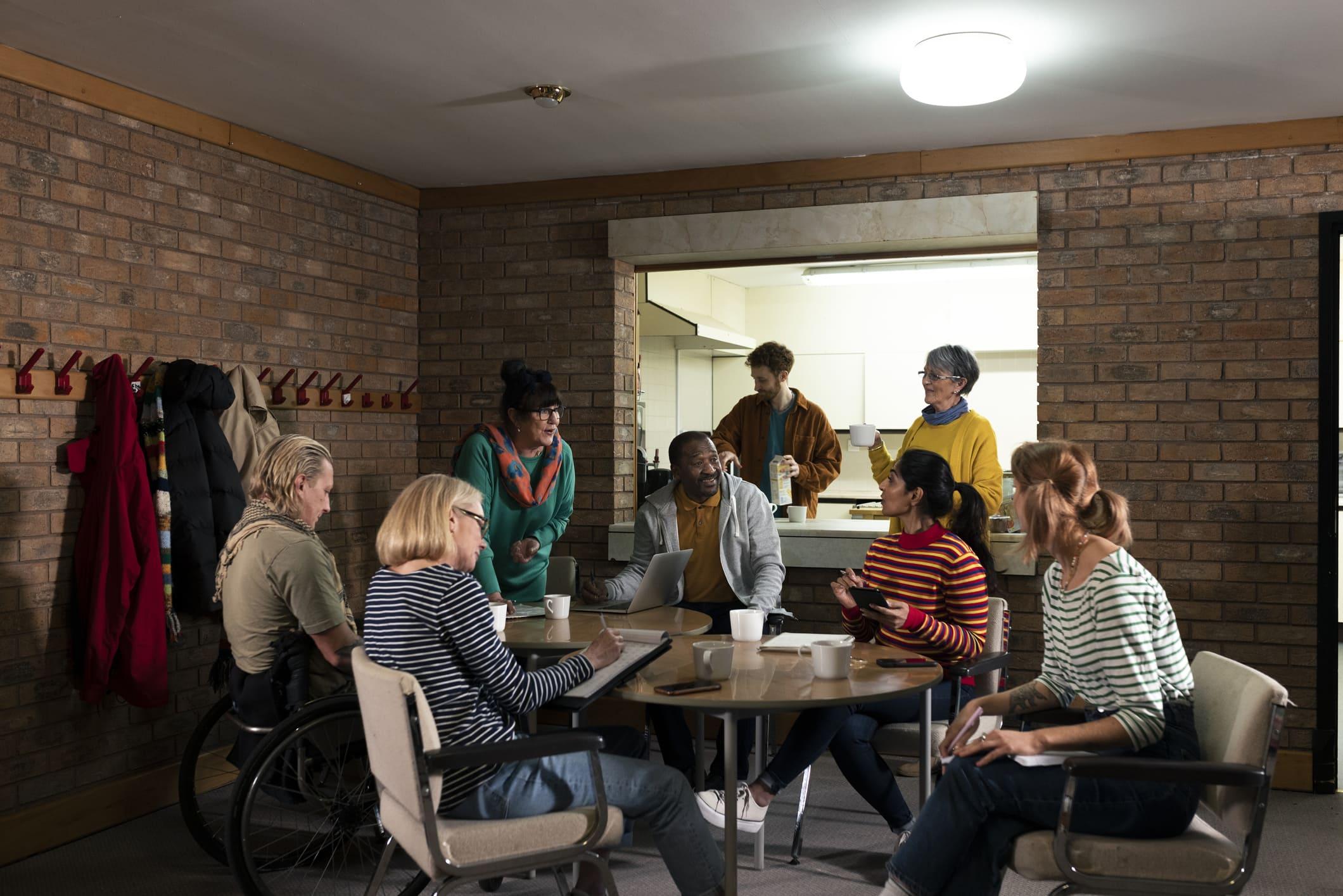 Gemeinde entscheidet über Kirchenasyl Eine Gruppe von Menschen sitzt in einem Gemeinderaum beisammen, darunter auch Menschen mit Migrationshintergrund. Sie bilden einen gemütlichen Sitzkreis.