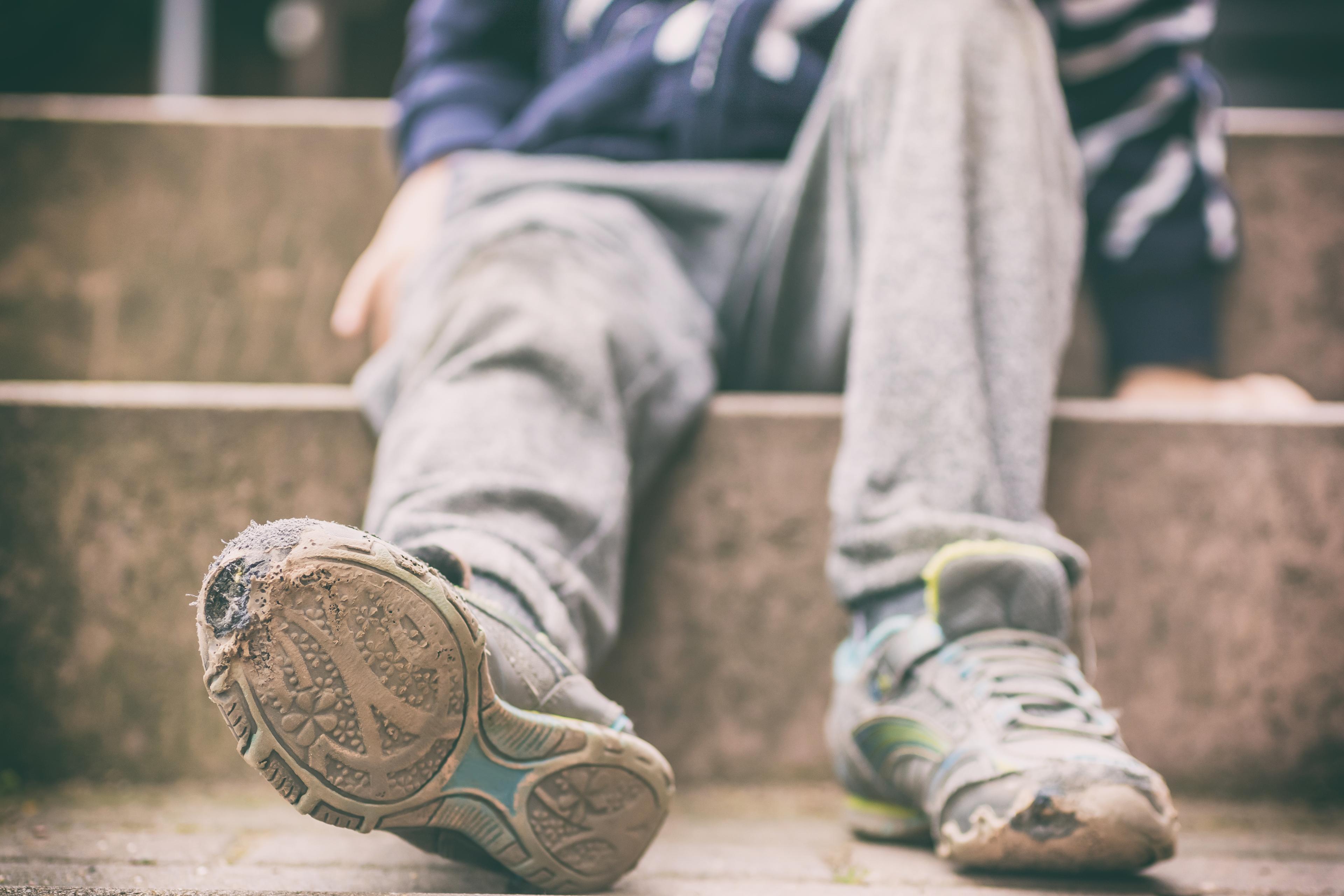 Kind mit abgetretenen alten Schuhen