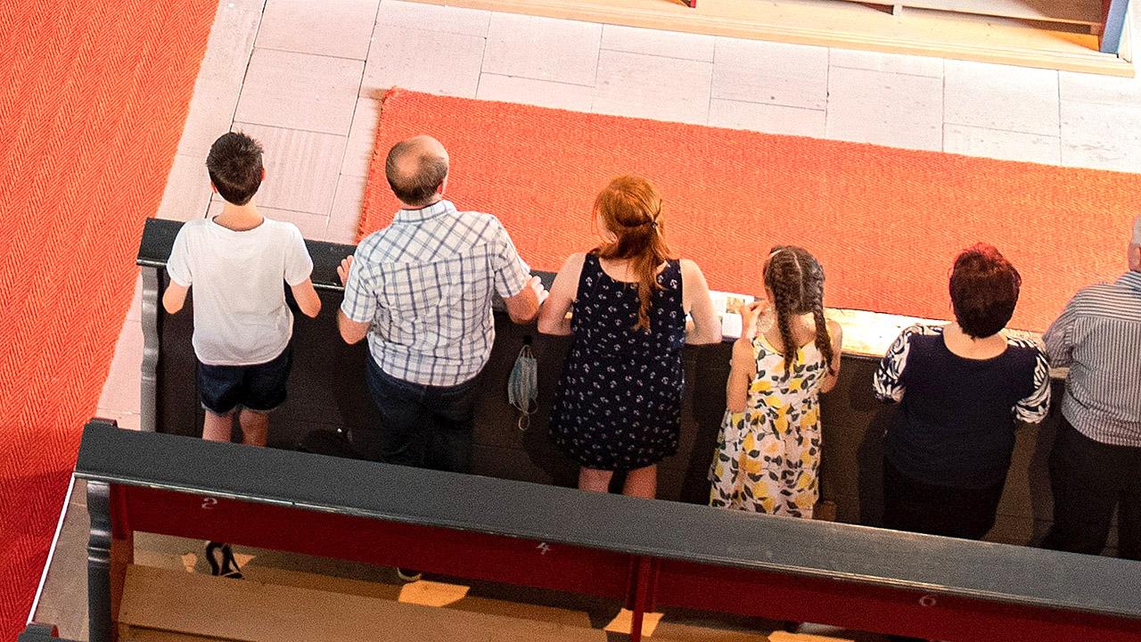 Glaubensbekenntnis Menschen stehen in einer Kirchenbank