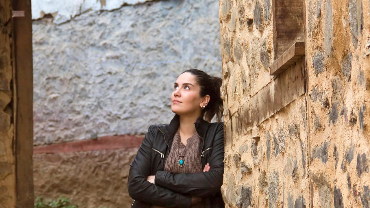 Eine Frau blickt nach oben, sie steht zwischen dicken Mauern