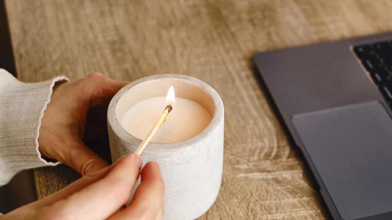 Kerze wird neben einem Laptop angezündet