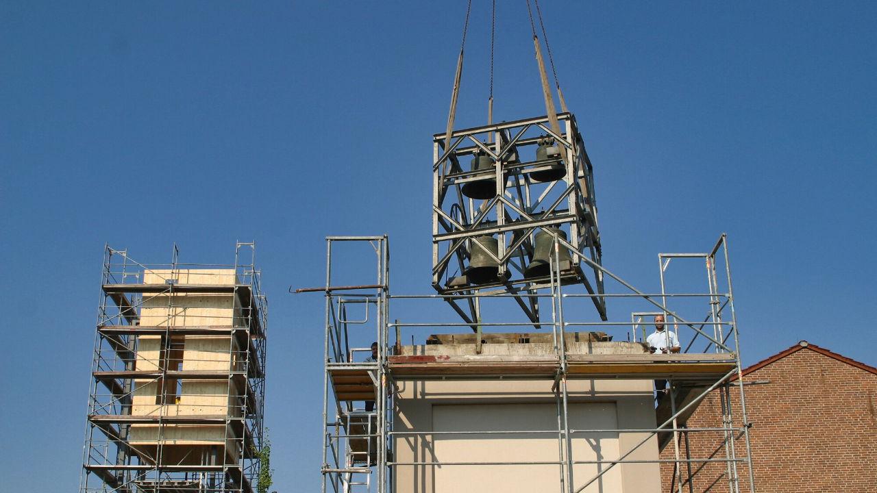 Eine neue Glocke schwebt über einem Kirchendach