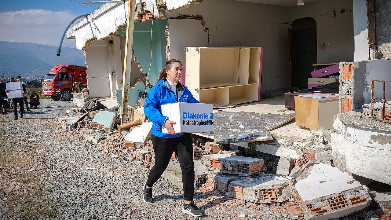 Frau trägt Karton mit Hilfsgütern im Erdbebengebiet