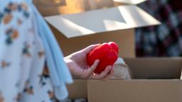 Eine Frau holt aus einem Karton eine rote Paprika