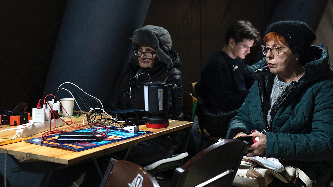 Winterhilfe Ukraine Menschen sitzen vor dunklem Hintergrund in einem Zelt