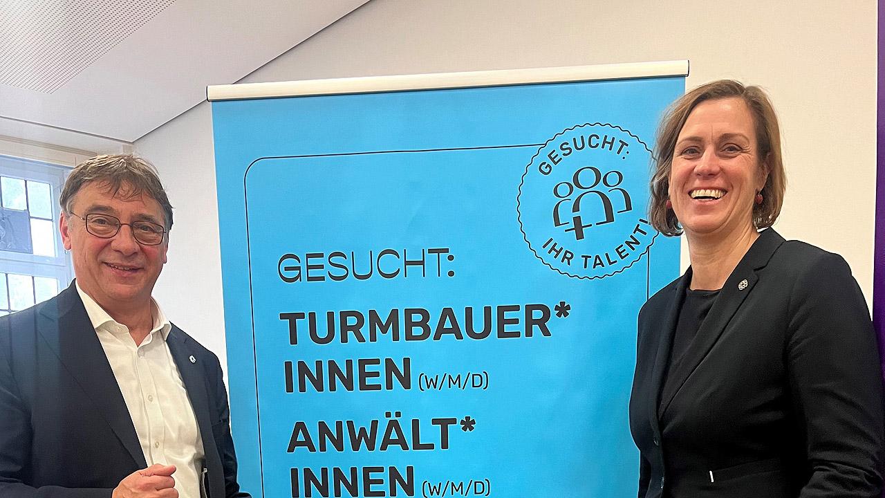 Impulspost Links der Kirchenpräsident, rechts die Pröpstin, in der Mitte das Plakat mit Berufsbezeichnungen