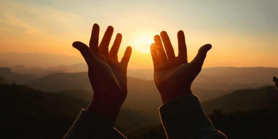 Ausgetreckte Hände zum Himmel Ausgetreckte Hände, die zum Himmel zeigen, an dem gerade die Sonne untergeht.