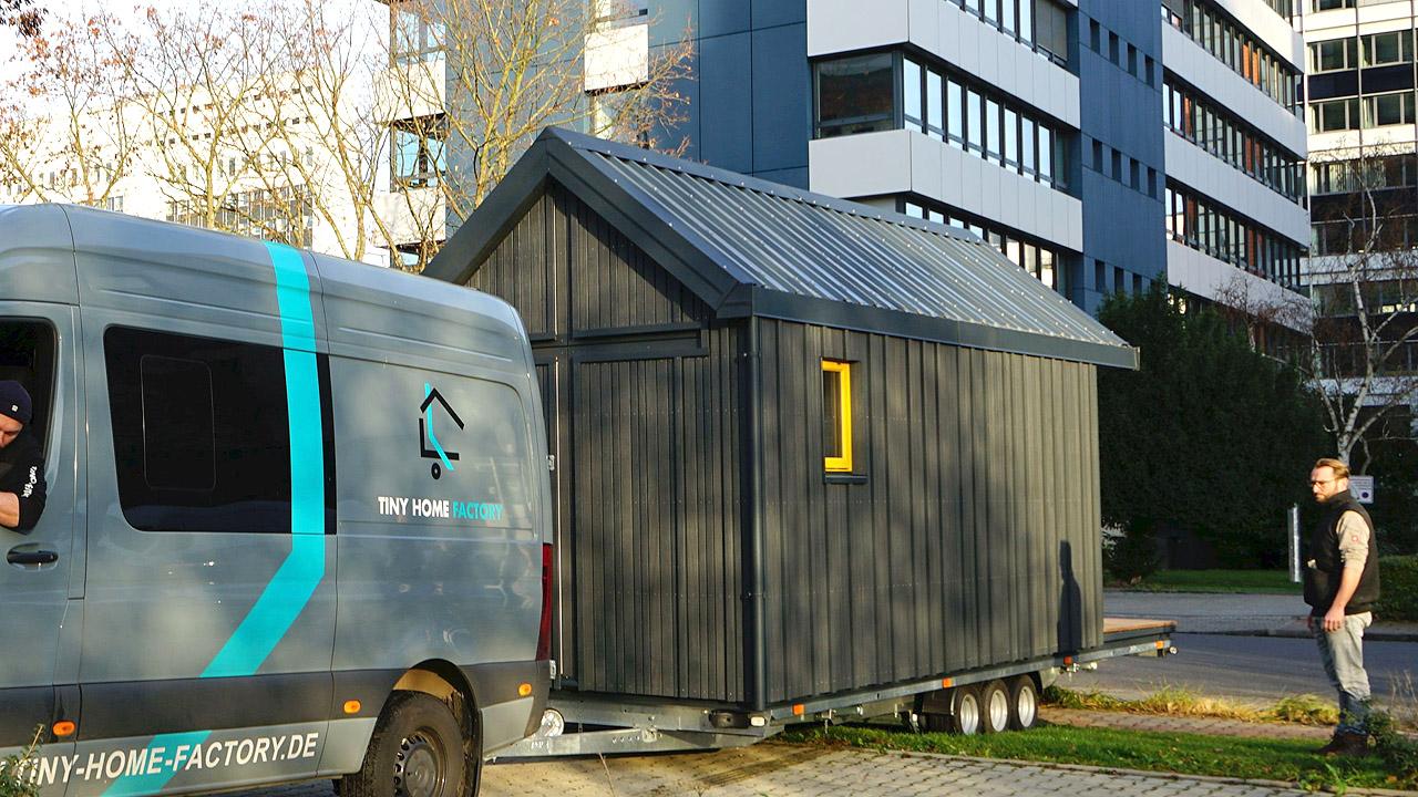 Kleine, schwarz gestrichene Kirche in Form eines Hüttchens auf einem Anhänger