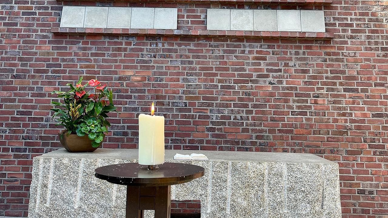 Granitaltar Granitaltar mit Blumenschmuck, davor eine Kerze