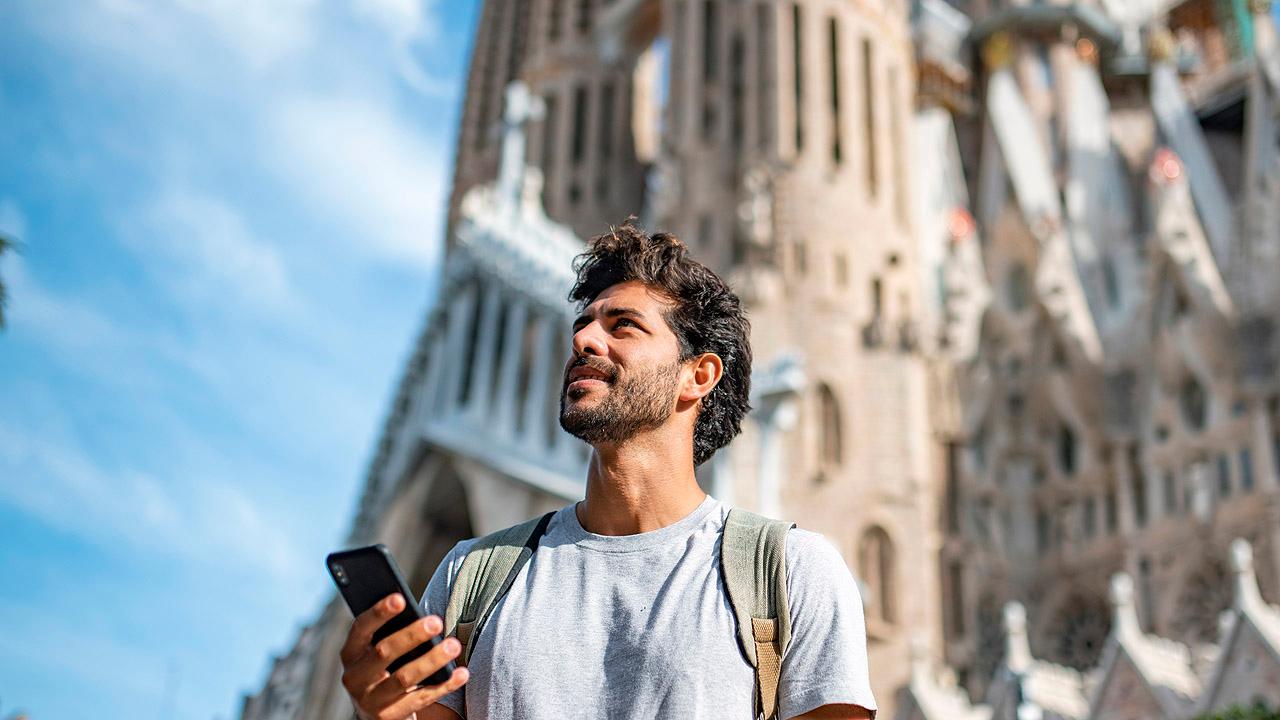 Junger Mann mit Smartphone vor der Sagrada Família