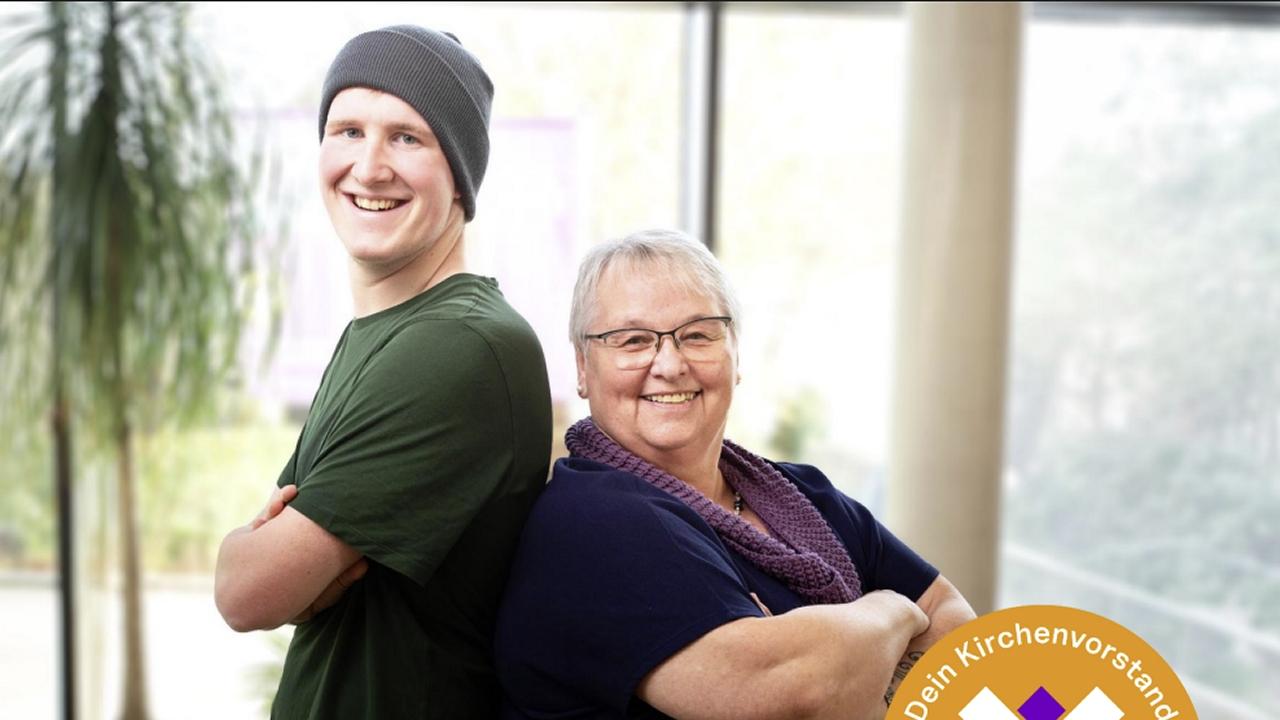 Zwei Personen – ein junger Mann mit Mütze und eine ältere Frau mit Brille – stehen Rücken an Rücken, lächeln in die Kamera und verschränken die Arme. Im Hintergrund ist ein heller Innenraum mit Pflanzen und großen Fenstern zu sehen. Unten rechts befindet sich ein grafisches Element zum Kirchenvorstand.
